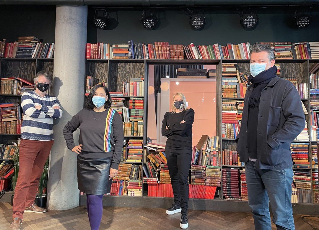 Erling Fossen, Nazneen Khan-Østrem, Maren Bjerkeng og Adnan Harambasic står foran en bokhylle fylt med bøker. Alle har på seg munnbind og ser mot kamera.